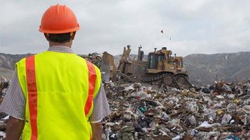 Landfill worker watching bulldozer
