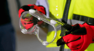 Employee wearing safety vest holding safety glasses