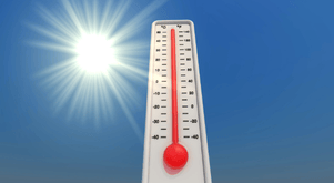 Blue sky with bright sun in background, a thermometer in center.