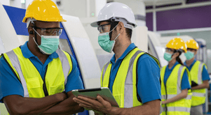 Employees wearing safety vests, hard hats, and face masks.