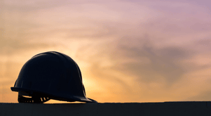 Sunset background with silhouette of hard hat.