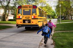 children running toward yellow school bus on road in neighborhood