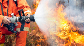 Firefighter using water hose to put out fire.