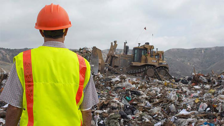 Landfill worker overseeing bulldozer