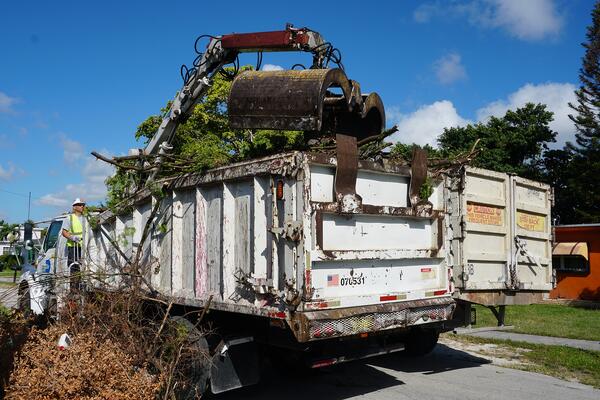 Maimi waste collectors putting yard waste in a dumpster