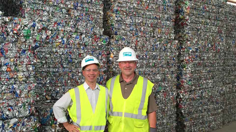 Two men standing in front of aluminum recycling